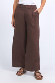 A model wearing the Pierra Linen Pant in colour Chocolate, from the front, cropped image