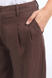 A model wearing the Pierra Linen Pant in colour Chocolate, from the front, cropped image