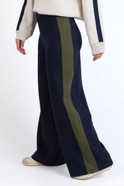 A model wearing the Juno Pant in colour Navygreen (Blue), from the front, cropped image