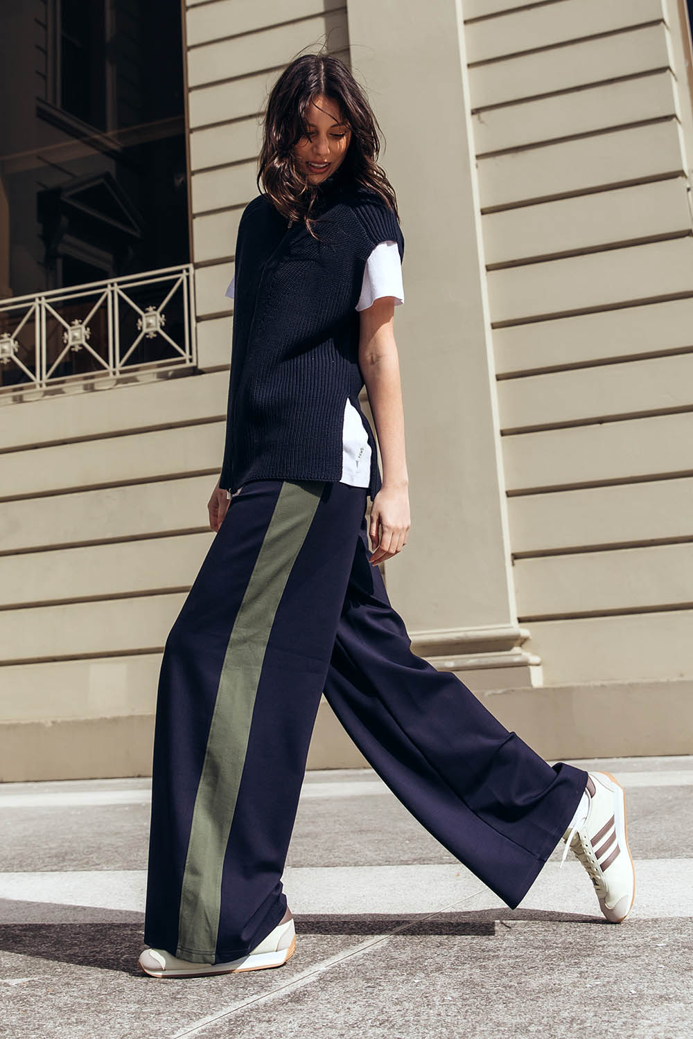 A model wearing the Juno Pant in colour Navygreen (Blue), from the front, showing the whole outfit