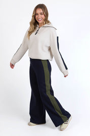 A model wearing the Juno Pant in colour Navygreen (Blue), from the front, showing the whole outfit