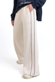 A model wearing the Traveller Pant in colour Bone, from the front, cropped image
