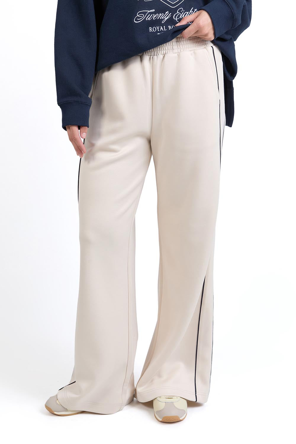 A model wearing the Traveller Pant in colour Bone, from the front, cropped image