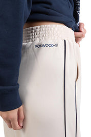 A model wearing the Traveller Pant in colour Bone, from the front, cropped image