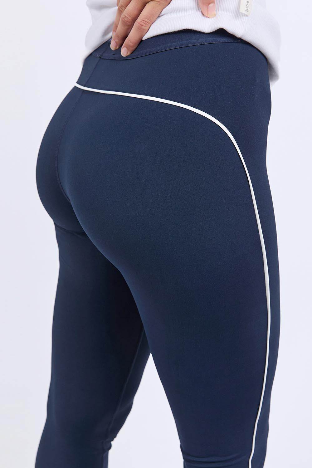 A model wearing the Elements Piping Leggings in colour Navy (Blue), from the front, cropped image