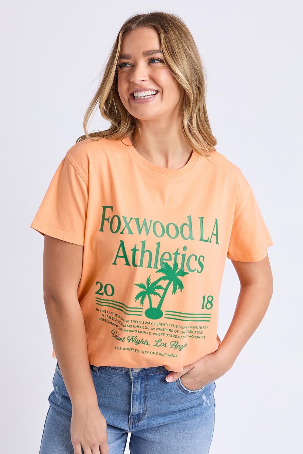 A model wearing the LA Aths Cotton Tee in colour Peach, from the front, cropped image
