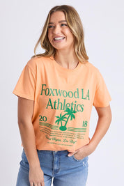 A model wearing the LA Aths Cotton Tee in colour Peach, from the front, cropped image
