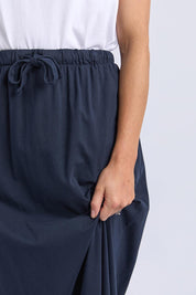 A model wearing the Evolve Cotton Skirt in colour Navy (Blue), from the front, cropped image