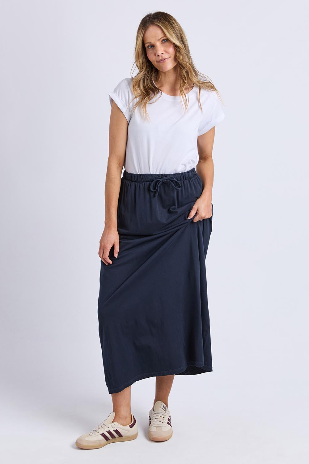 A model wearing the Evolve Cotton Skirt in colour Navy (Blue), from the front, showing the whole outfit