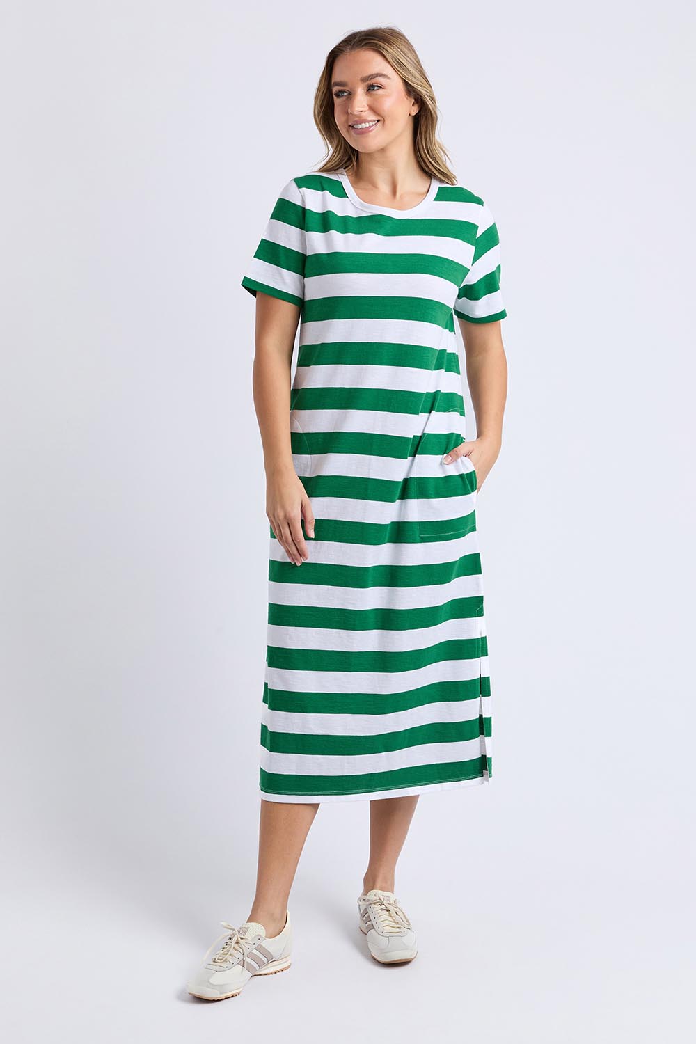 A model wearing the Tallow Cotton Dress in colour Whtgreen, from the front, showing the whole outfit