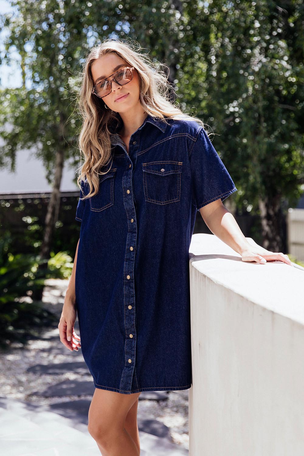 A model wearing the Sorcha Denim Dress in colour Indigoden (Blue), from the front, showing the whole outfit