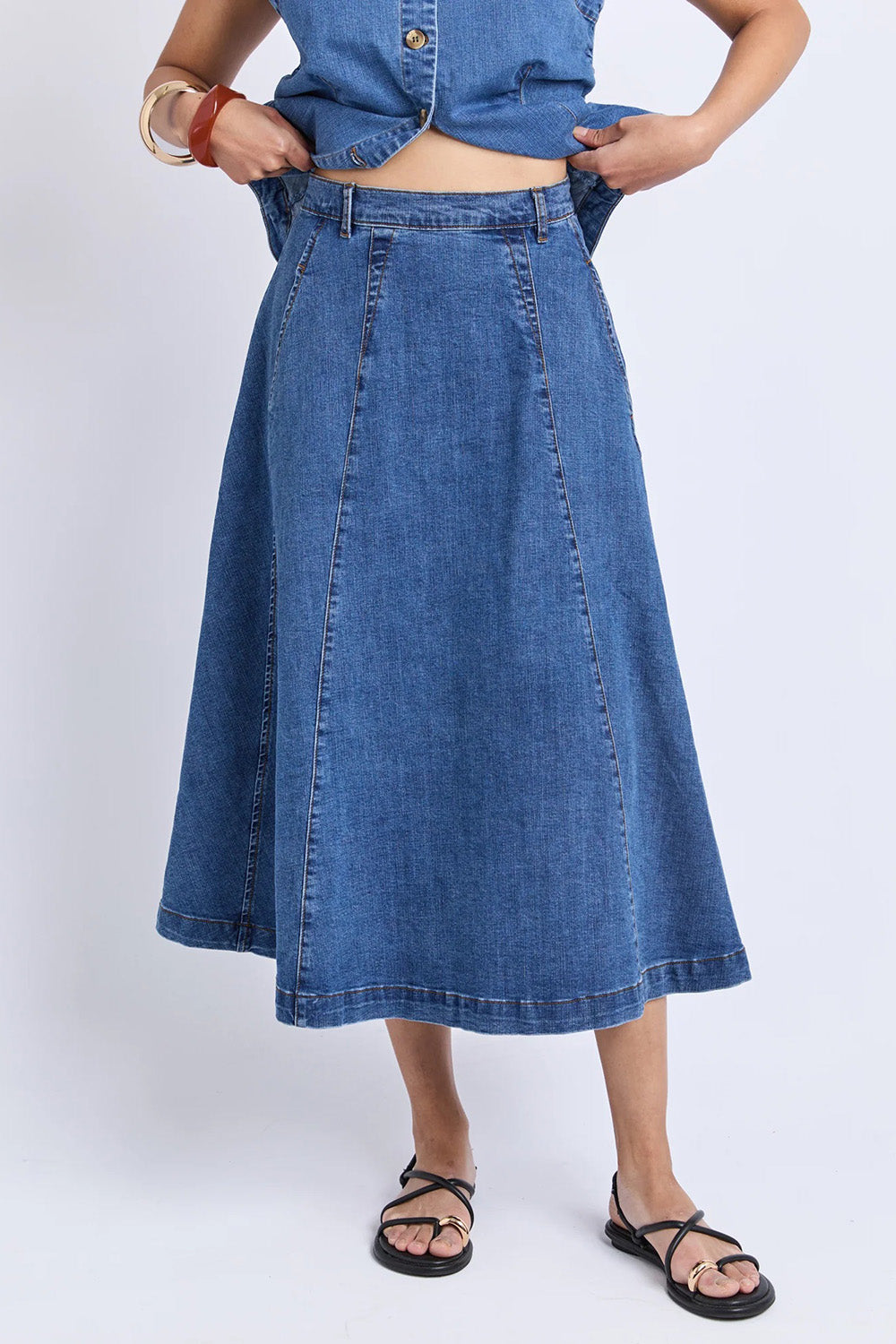 A model wearing the Abbott Denim Skirt in colour Midblue (Blue), from the front, cropped image