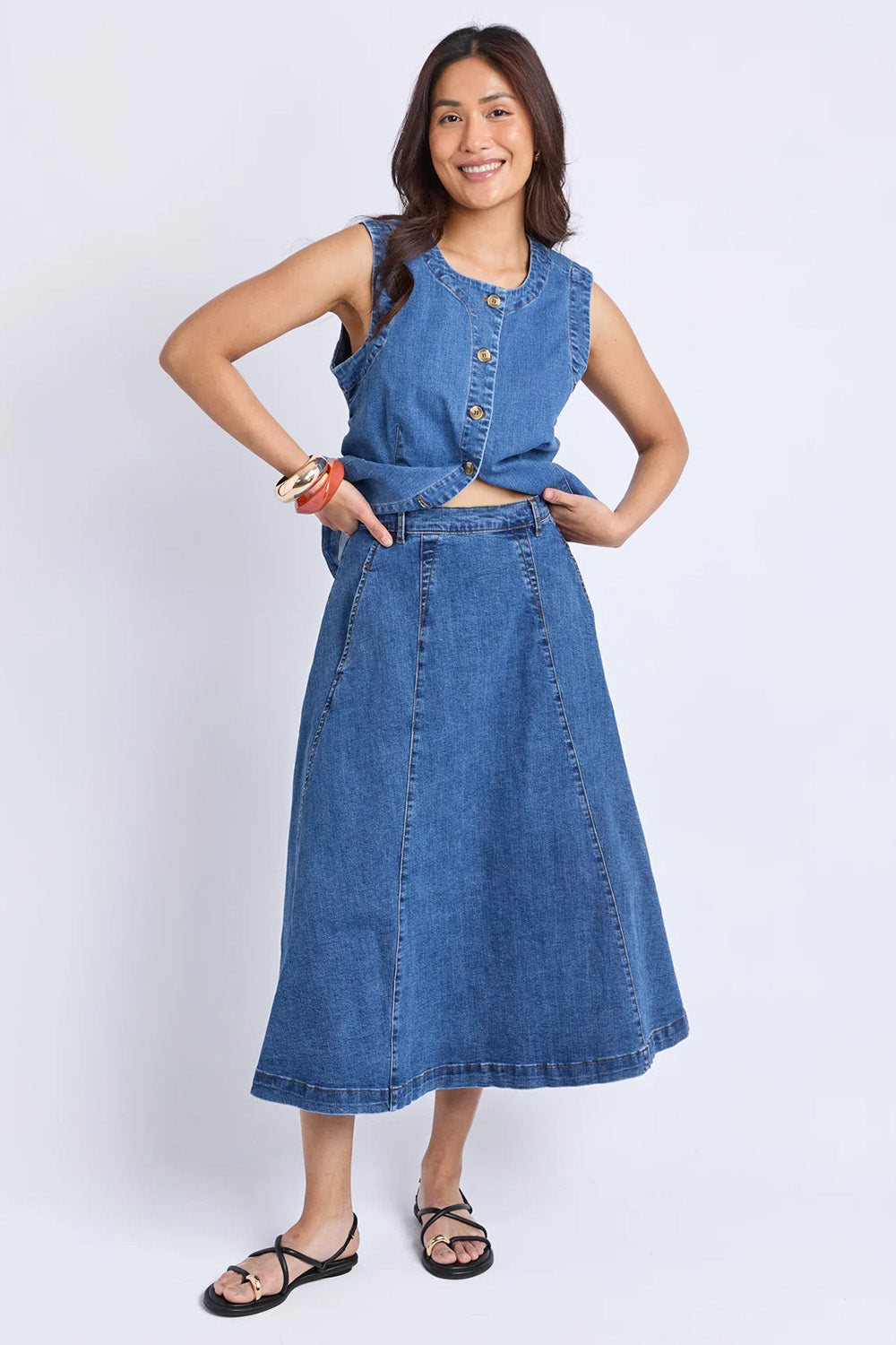 A model wearing the Abbott Denim Skirt in colour Midblue (Blue), from the front, showing the whole outfit