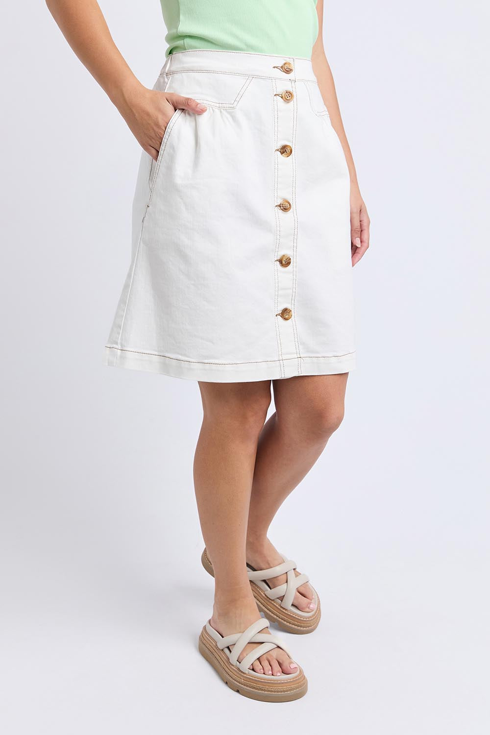A model wearing the Elements Amanda Denim Skirt in colour White (White), from the front, cropped image