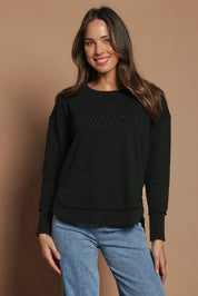 Model Madeline wearing size 10 of the Elements Simplified Cotton Crew in colour Black (Black), from the front, cropped image