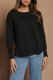Model Madeline wearing size 10 of the Elements Simplified Cotton Crew in colour Black (Black), from the front, cropped image