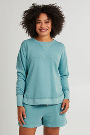Model Olivia wearing size 10 of the Elements Simplified Cotton Crew in colour Sky (Blue), from the front, cropped image