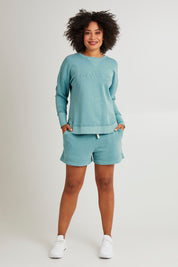 Model Olivia wearing size 10 of the Elements Simplified Cotton Crew in colour Sky (Blue), from the front, showing the whole outfit