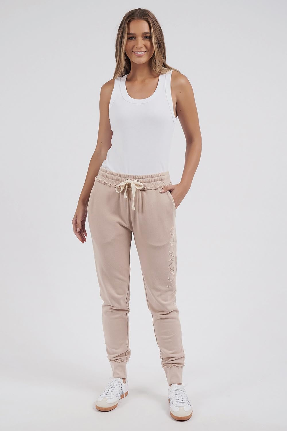 A model wearing the Leisure Simplified Pants in colour Oatmeal, from the front, showing the whole outfit
