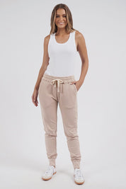 A model wearing the Leisure Simplified Pants in colour Oatmeal, from the front, showing the whole outfit