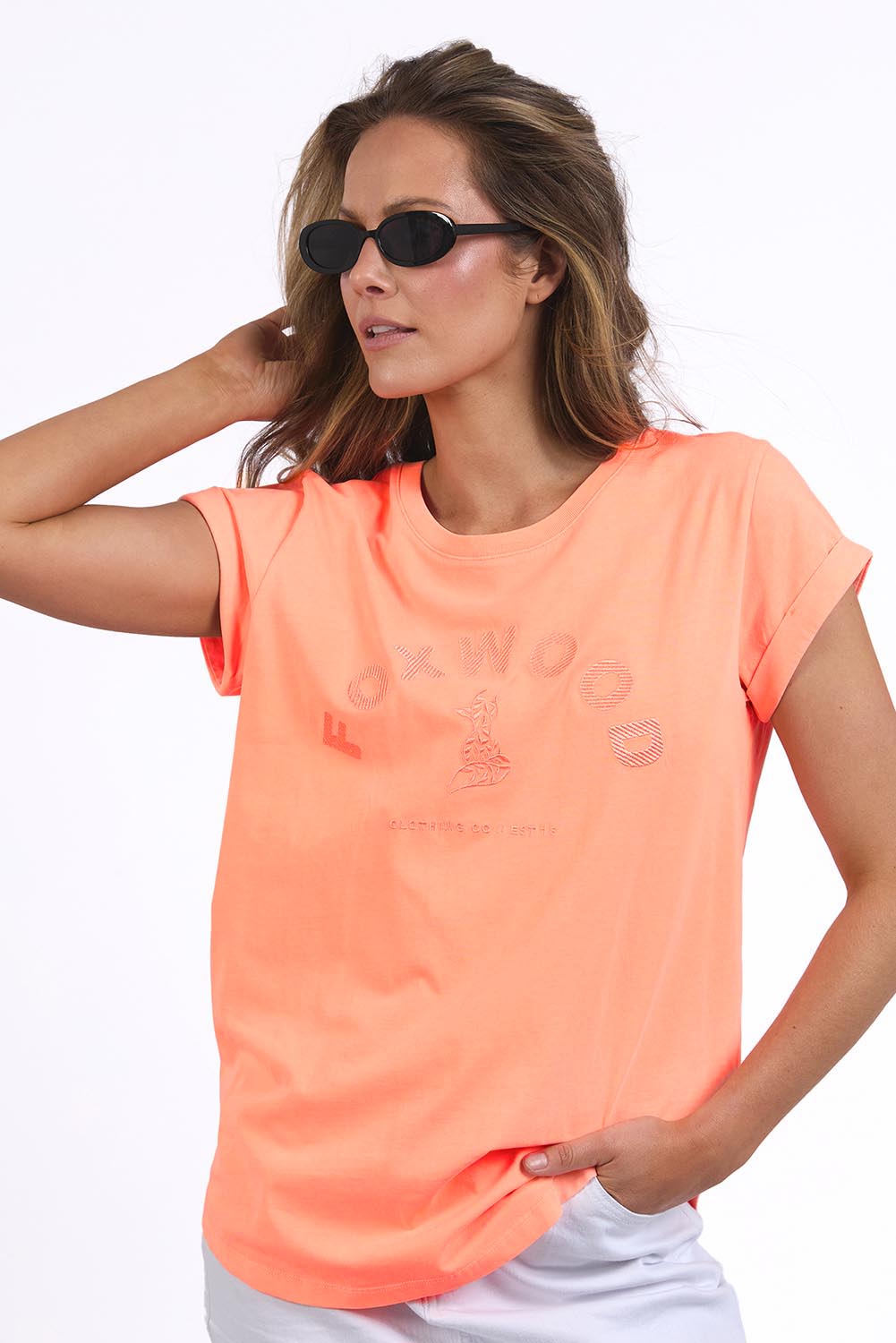 A model wearing the Elements Effortless Tee in colour Neonpeach, from the front, cropped image