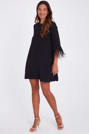 Model Alex wearing size 10 of the Enchanted Feather Sleeve Dress in colour Black (Black), from the front, showing the whole outfit