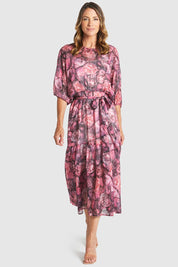 A model wearing the Phenomenon Dress in colour Peony (Pink), from the front, showing the whole outfit
