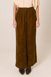 A model wearing the Intricate Velvet Pant in colour Gold, from the front, cropped image