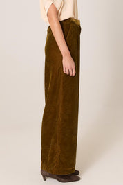 A model wearing the Intricate Velvet Pant in colour Gold, from the front, cropped image