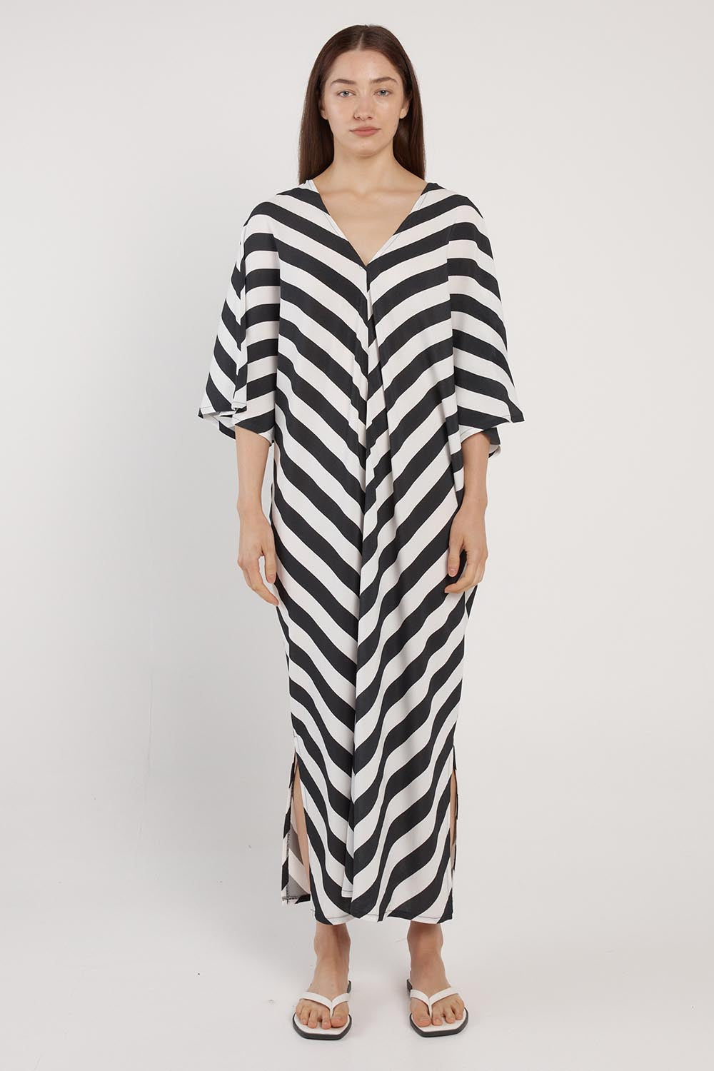 A model wearing the Madeira Dress in colour Liquorice (Black), from the front, showing the whole outfit