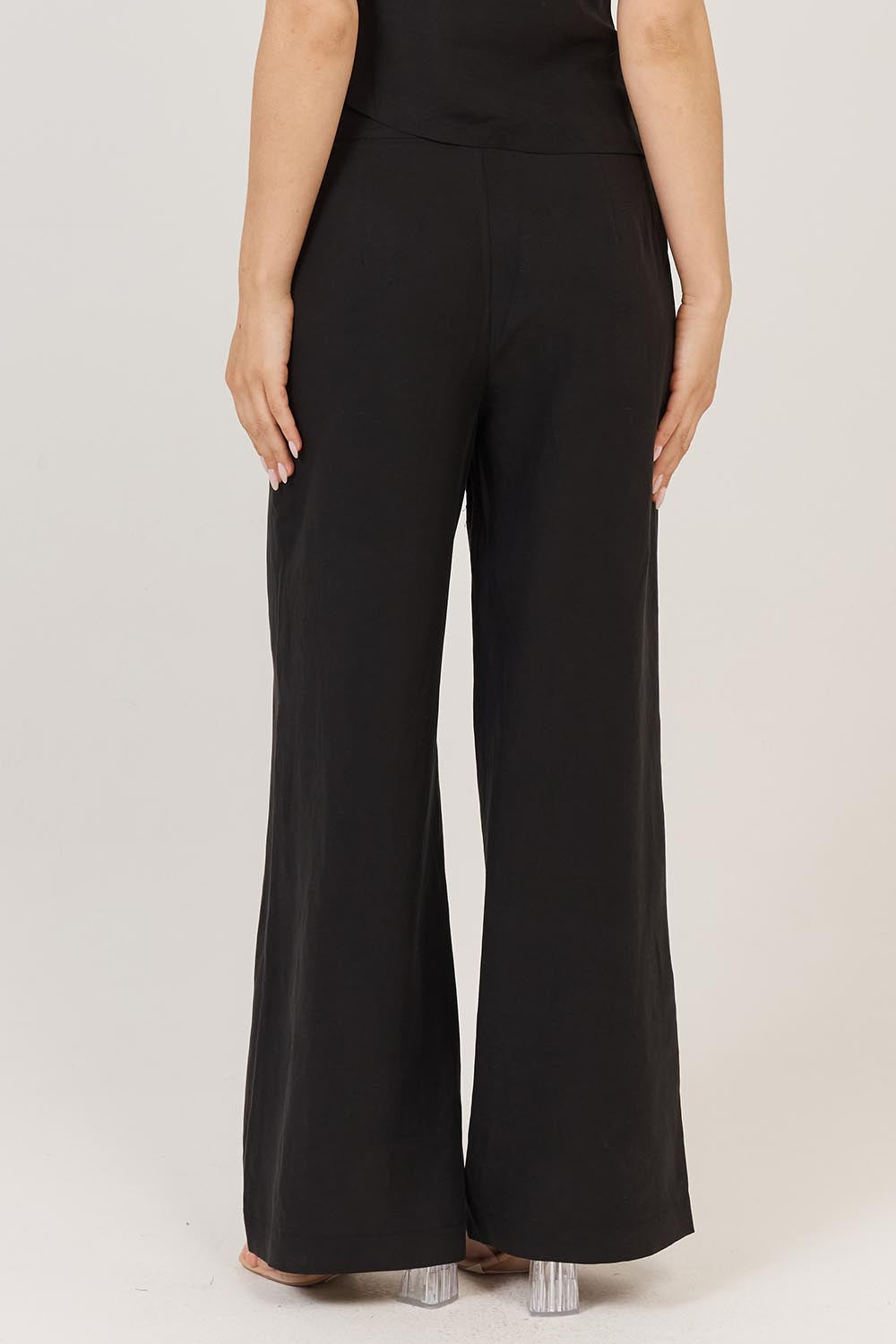 A model wearing the Sandara Pant in colour Black (Black), from the back