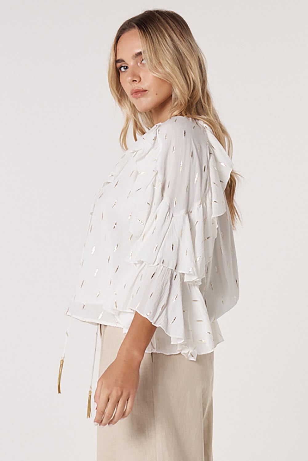 A model wearing the Delia Ruffle Top in colour White (White), from the front, cropped image