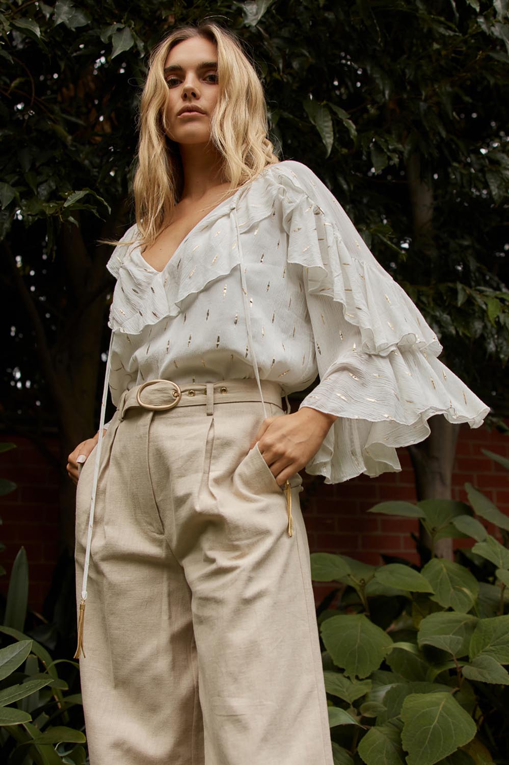 A model wearing the Delia Ruffle Top in colour White (White), from the front, showing the whole outfit