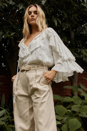 A model wearing the Delia Ruffle Top in colour White (White), from the front, showing the whole outfit