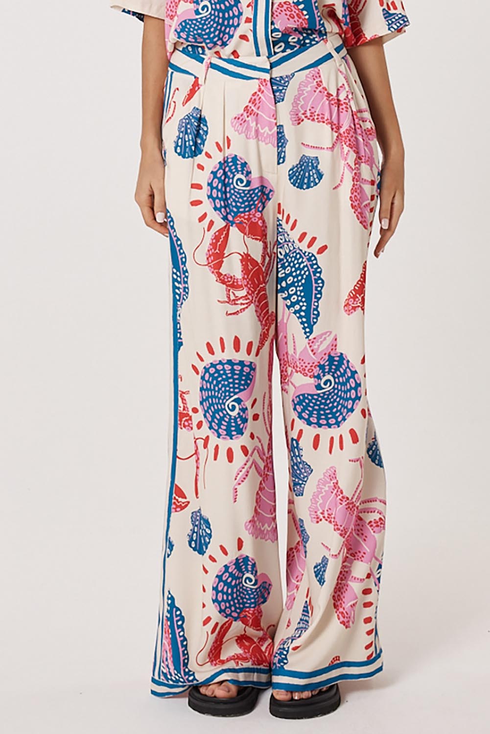 A model wearing the Soleil Pant in colour Lobster, from the front, cropped image