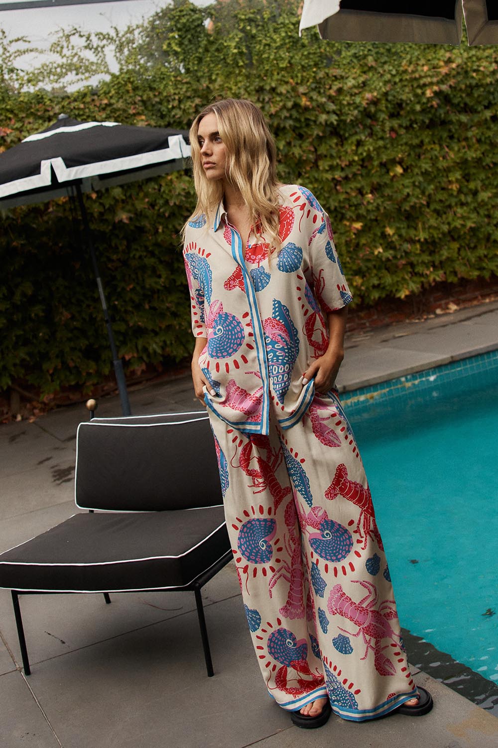 A model wearing the Soleil Pant in colour Lobster, from the front, showing the whole outfit