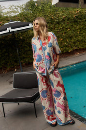 A model wearing the Soleil Pant in colour Lobster, from the front, showing the whole outfit