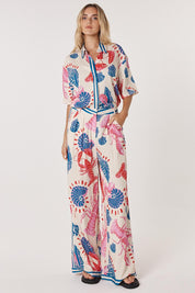 A model wearing the Soleil Pant in colour Lobster, from the front, showing the whole outfit