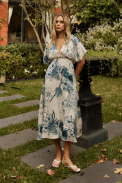 A model wearing the Solstice Palms Midi Dress in colour Palm (Blue), from the front, showing the whole outfit