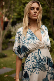 A model wearing the Solstice Palms Midi Dress in colour Palm (Blue), from the front, showing the whole outfit