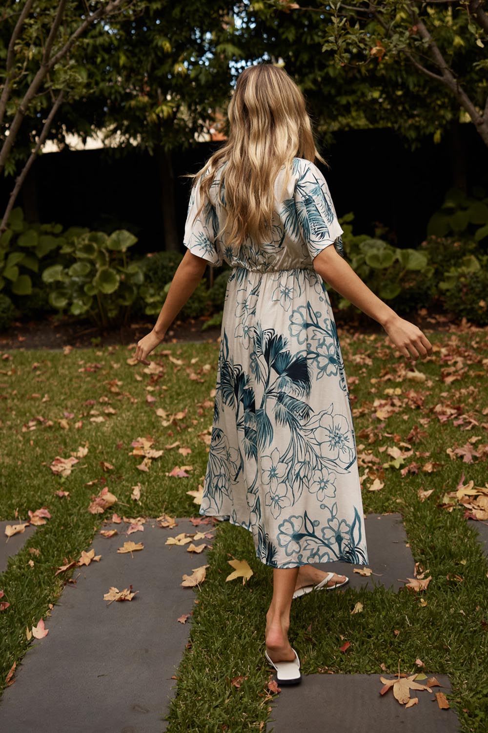 A model wearing the Solstice Palms Midi Dress in colour Palm (Blue), from the front, showing the whole outfit