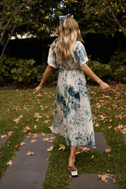 A model wearing the Solstice Palms Midi Dress in colour Palm (Blue), from the front, showing the whole outfit