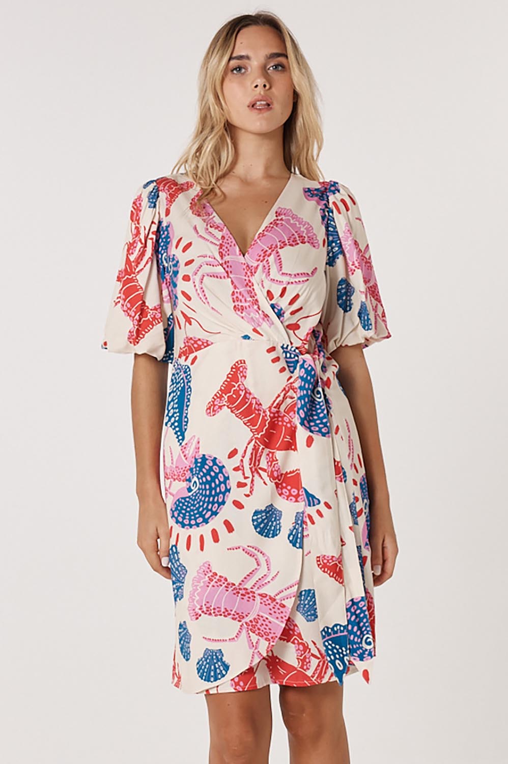 A model wearing the Soleil Wrap Dress in colour Lobster, from the front, cropped image