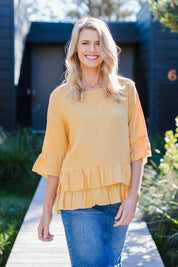 Model Kelly wearing size 10 of the Frilled Hem Top in colour Gold, from the front, showing the whole outfit