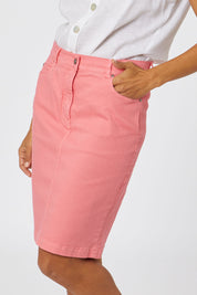 Model Cara wearing size 10 of the Miracle Denim Skirt in colour Coral (Pink), from the front, cropped image