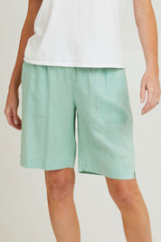 Model Grace wearing size 10 of the Jersey Waist Linen Short in colour Mint, from the front, cropped image