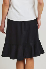 Model Olivia wearing size 10 of the Piccolo Linen Skirt in colour Black (Black), from the back