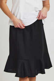 Model Olivia wearing size 10 of the Piccolo Linen Skirt in colour Black (Black), from the front, cropped image