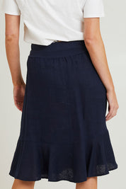 Model Grace wearing size 10 of the Piccolo Linen Skirt in colour Navy (Blue), from the back