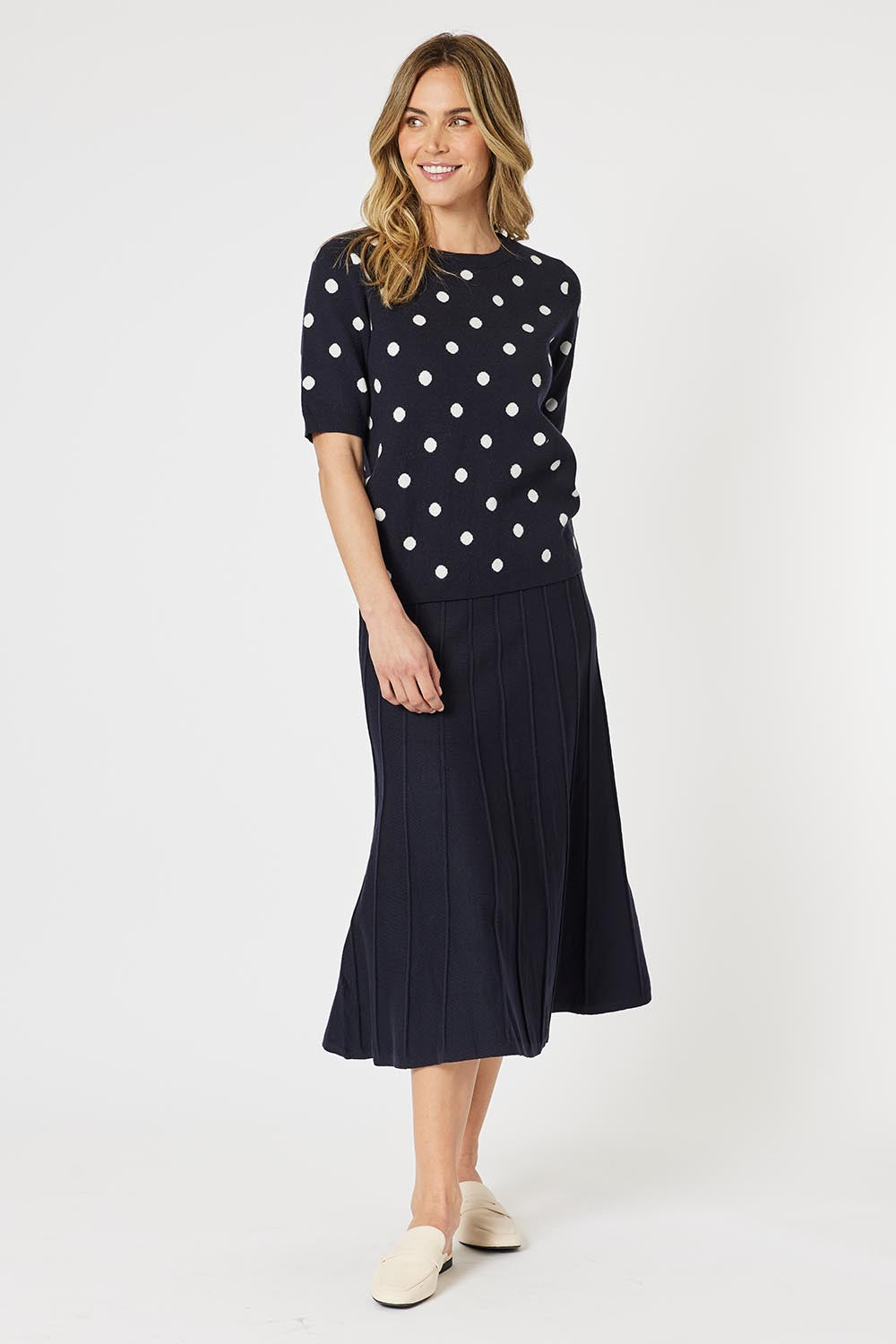 A model wearing the Kate Knit Long Skirt in colour Navy (Blue), from the front, showing the whole outfit